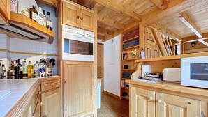 A kitchen with wooden cabinets, a microwave, and various kitchen appliances. - Copalme - appartement - 5/7 pers - Centre (Les Gets)