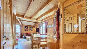 A wooden cabin interior with a dining area, a sofa, and a large mirror. - Copalme - appartement - 5/7 pers - Centre (Les Gets)