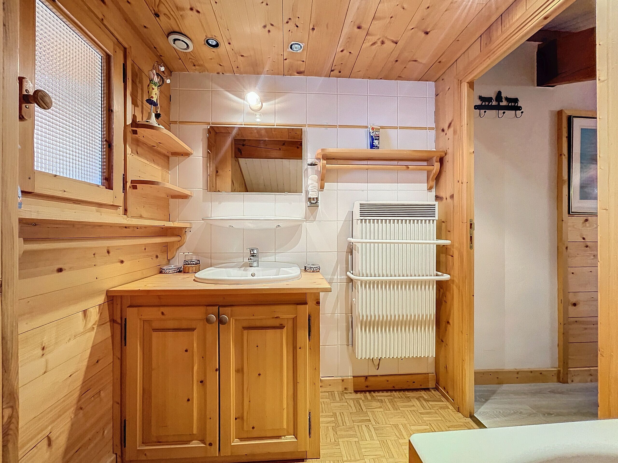 Ein Badezimmer mit Holzwandverkleidung, einem Waschbecken, einem Spiegel und einem Heizkörper.