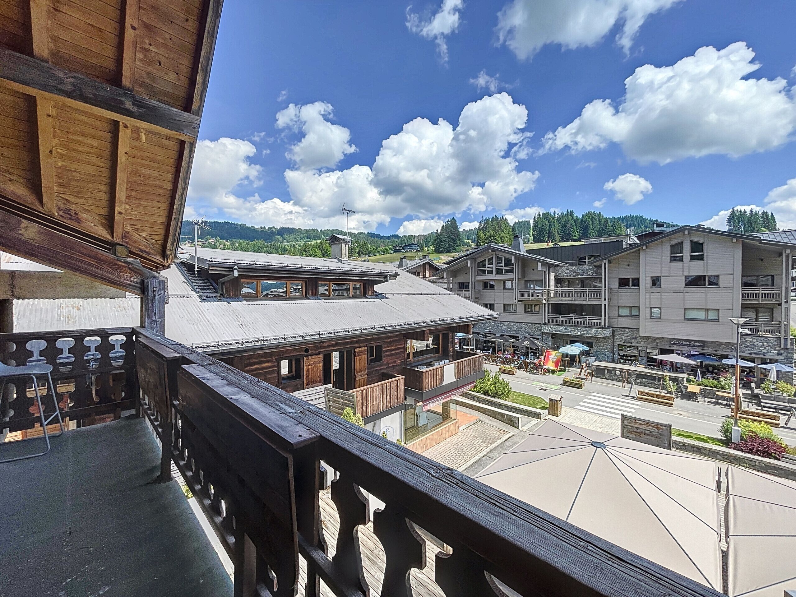 Ein hölzerner Balkon mit Blick auf einen Stadtplatz, Gebäude und einen Berg im Hintergrund.