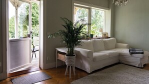 A living room with a white sofa, a potted plant, and a chandelier.