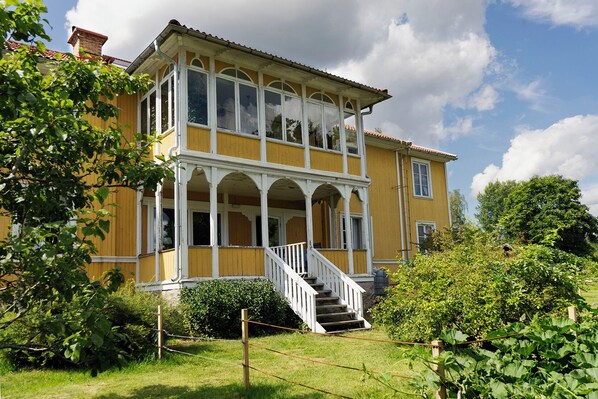 A two-story yellow building with a white staircase leading to a balcony.