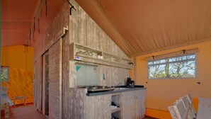 A compact kitchen with wooden cabinetry, a gas stove, and a window providing natural light. - Safari Tent Near Biesbosch & Breda (Oosterhout)