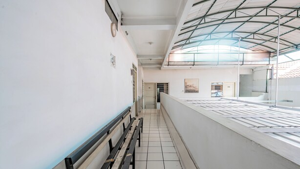 A corridor with benches, a tiled floor, and a high ceiling with a skylight. - Collection O Hotel Sanira (Bandung)