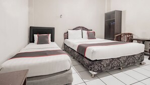 A hotel room with two single beds, a wooden chair, a desk, and a wardrobe. - Collection O Hotel Sanira (Bandung)