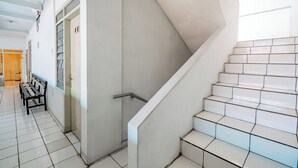 A staircase with white tiles and a metal handrail, leading to an upper floor. - Collection O Hotel Sanira (Bandung)