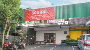 A hotel named Sanira with a large red banner, a parking area, and a few parked motorcycles. - Collection O Hotel Sanira (Bandung)