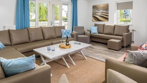 Una sala de estar moderna con un sofá modular, una mesa de centro y dos sillones.
