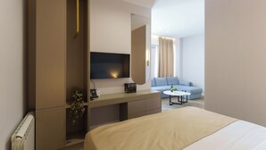 Une chambre d’hôtel moderne dotée d’un grand lit, d’un bureau avec un téléviseur à écran plat, d’un canapé et d’une table basse.