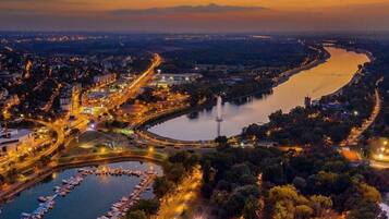 Vista aérea de una ciudad costera al anochecer, con un puerto deportivo, calles y edificios.
