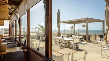Relax under a shaded pergola with a view of the ocean through large windows.