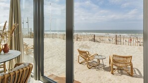 A beach view from a room with wicker furniture and a glass door. - Beach House in Zandvoort With Sea View (Zandvoort)