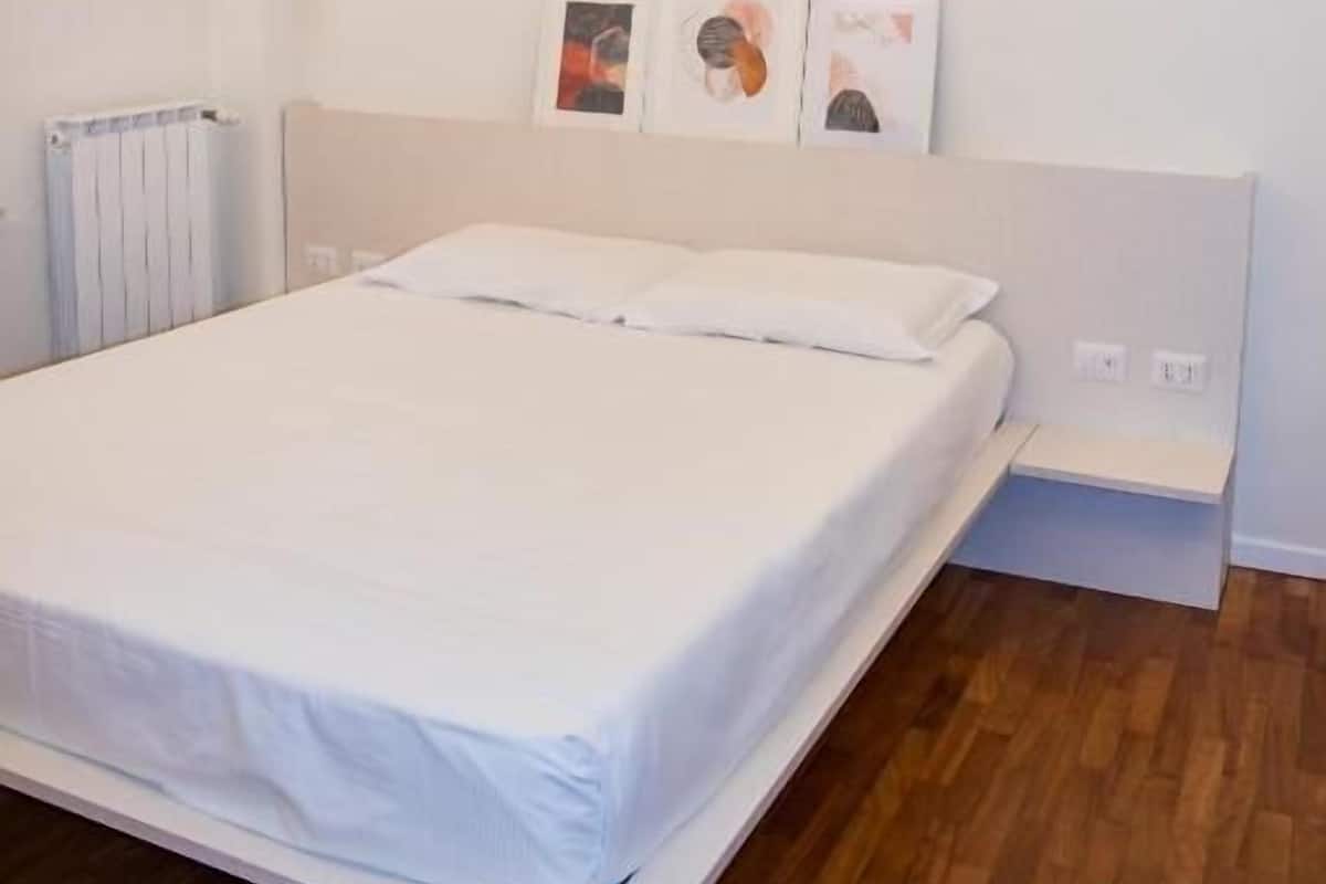 A bedroom with a bed, a bedside table, and a radiator.