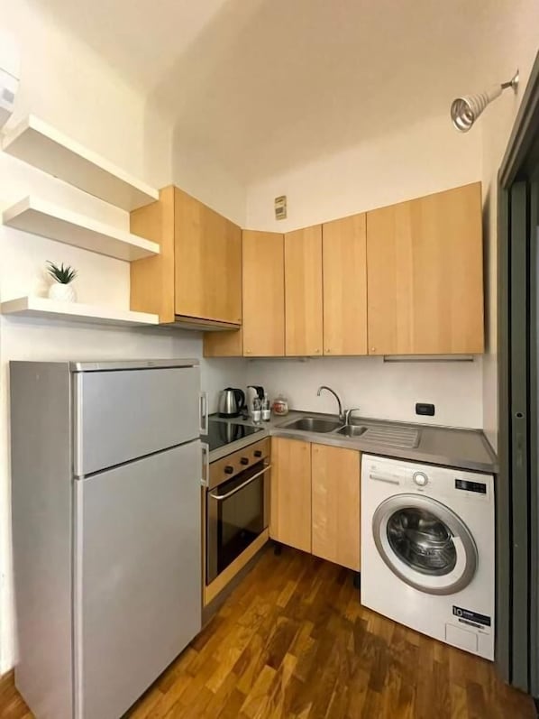 A compact kitchen with a refrigerator, oven, sink, and washing machine. - Easy Milano Rooms & Apartments (Milan)