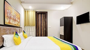 A hotel room with a bed, a painting of horses, a wardrobe, and a television. - Hotel Shashwat (Gorakhpur)