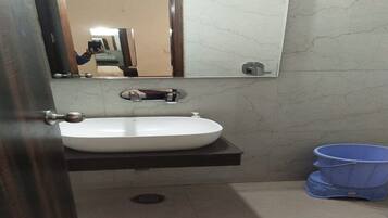 A bathroom with a white sink, a mirror, and a blue bucket.