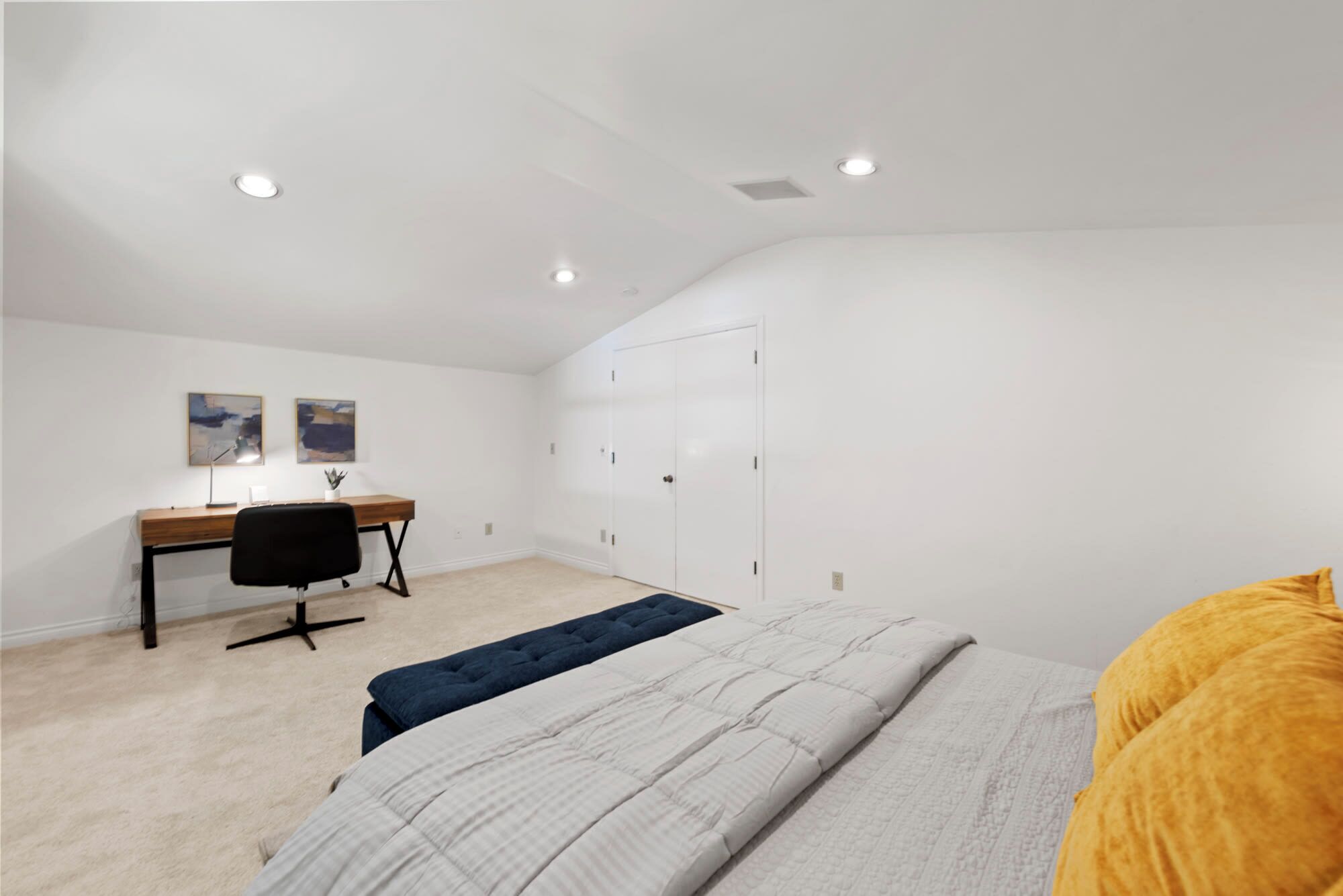 A bedroom with a bed, a desk, a chair, and a wardrobe.