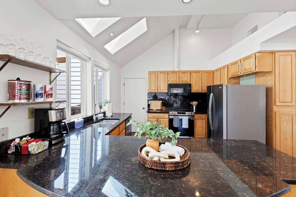 Una cocina moderna con una isla central, armarios de madera y un refrigerador de acero inoxidable.