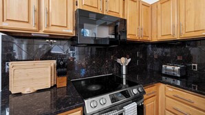 A kitchen with wooden cabinets, a black microwave, a stove, and a toaster. - Stunning Sammamish Lake View Home near Weowna Park (Bellevue)