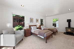 A bedroom with two beds, a sofa, a fireplace, and large windows. - Stunning Sammamish Lake View Home near Weowna Park (Bellevue)