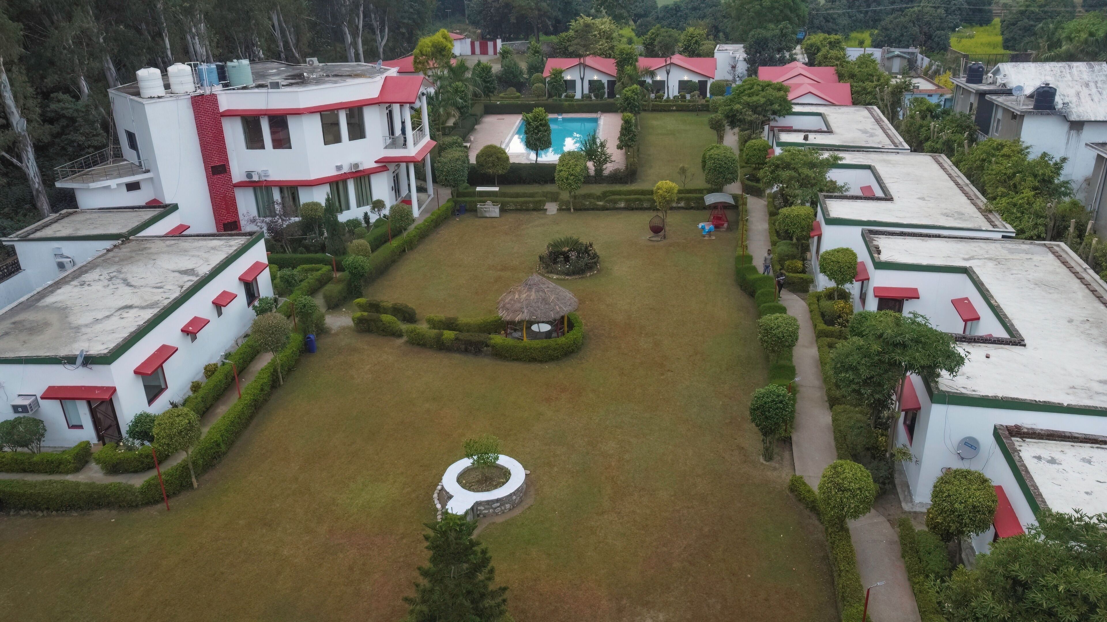 A residential area with multiple buildings, a central swimming pool, and well-maintained gardens.