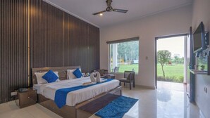A modern bedroom with a large bed, a view of the outdoors, and a ceiling fan. - Corbett Holiday Forest Resort (Belparao)