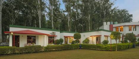 A hotel with multiple buildings, each with a red roof and white walls, surrounded by a well-maintained lawn and trees.