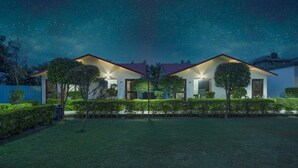 A modern house with a well-maintained lawn and a clear night sky. - Corbett Holiday Forest Resort (Belparao)