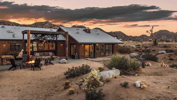 A desert-style building with a fire pit, outdoor seating, and a view of the mountains.