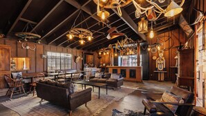 A rustic interior with wooden beams, leather furniture, and unique lighting fixtures.