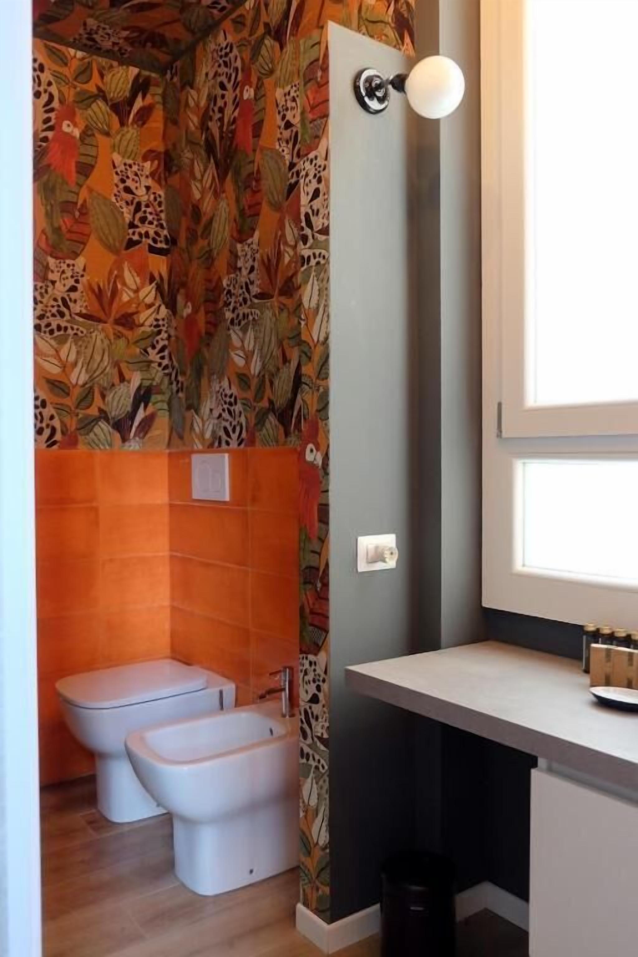 A bathroom with a toilet, bidet, and a window.