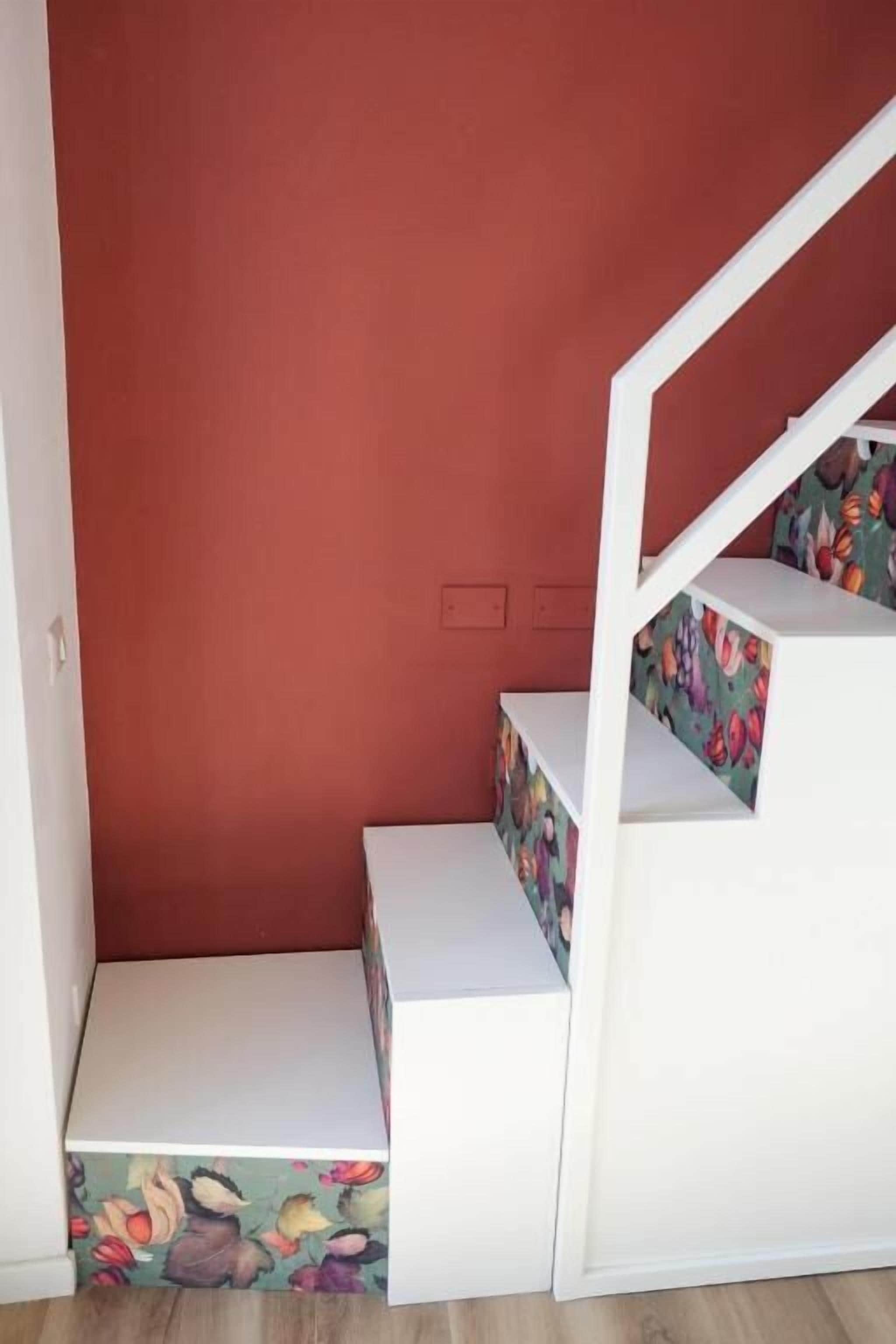 Una escalera con escalones blancos y un rellano con estampado floral.