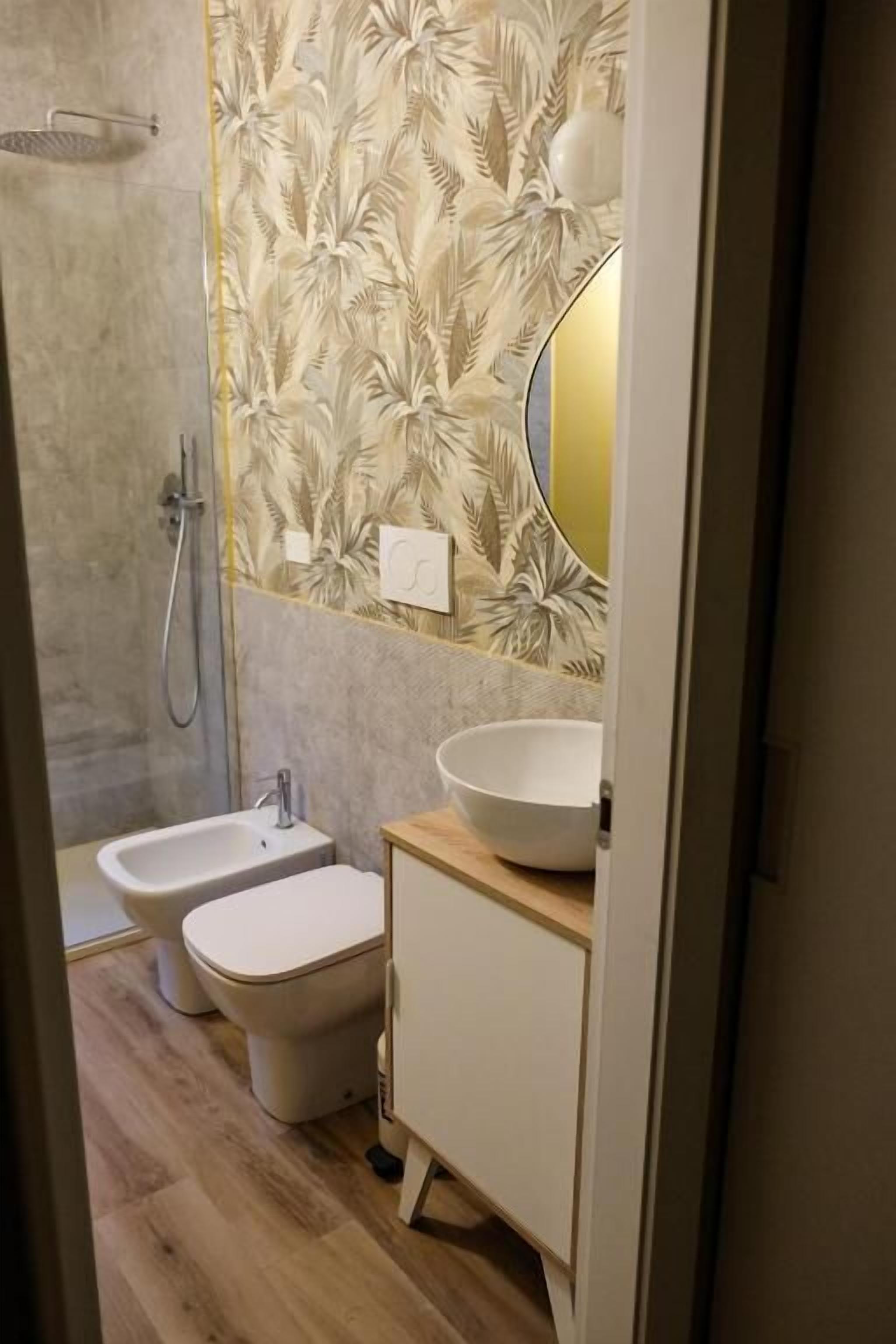 Une salle de bain moderne équipée d’une douche, de deux bidet, d’un lavabo et d’un miroir.