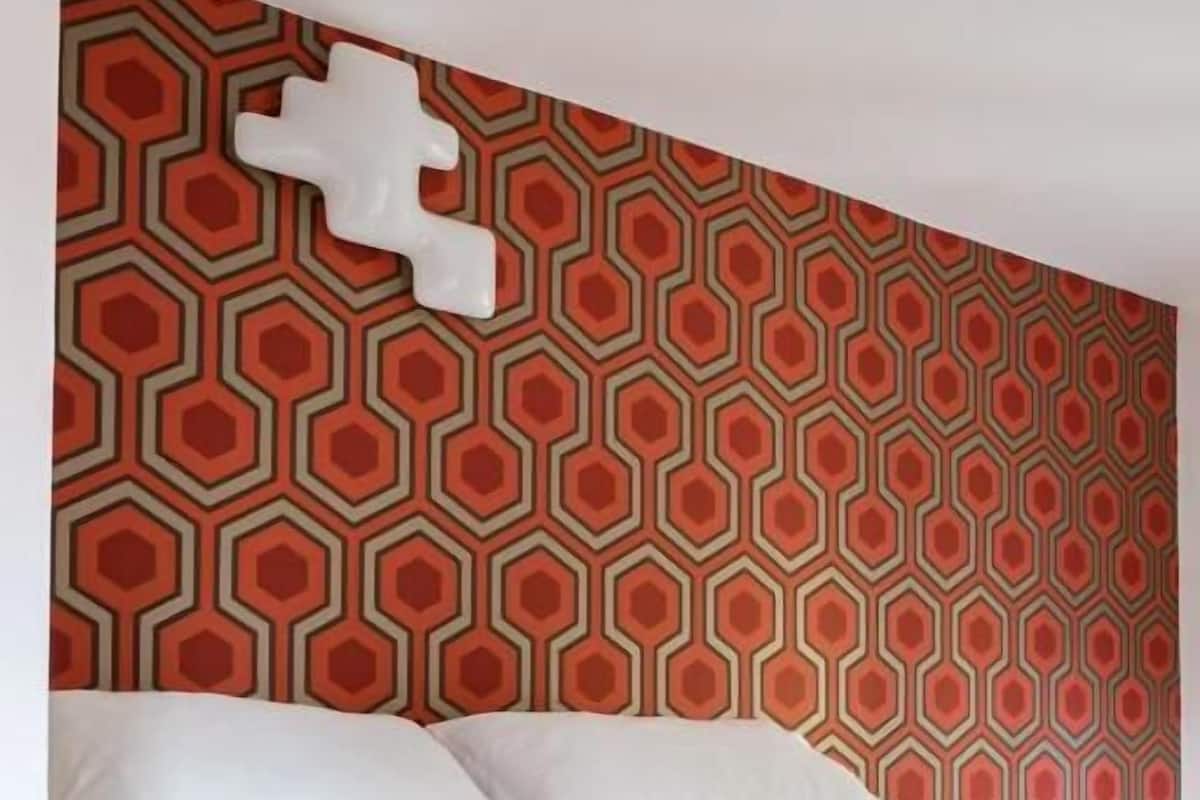 A bed with white bedding in a room with a geometric patterned wall.
