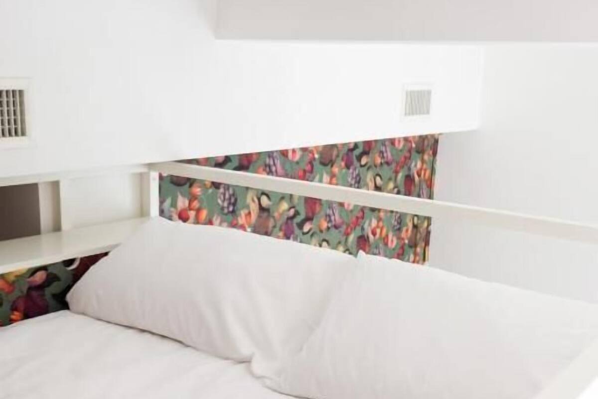 A bed with white bedding and a colorful headboard.