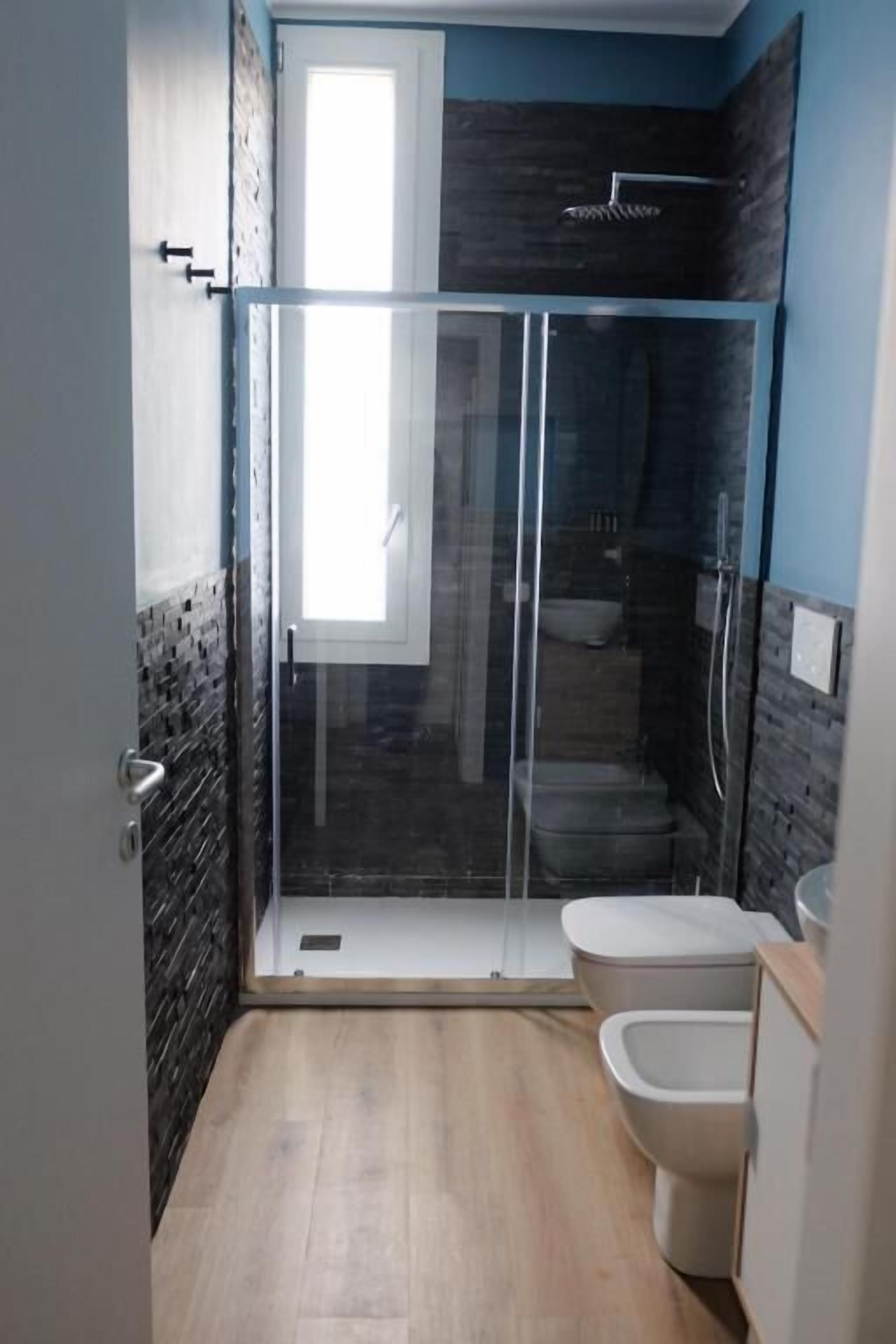 Une salle de bain moderne dotée d’une douche à parois de verre, de toilettes et d’un bidet.