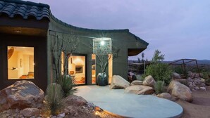 A modern house with a curved roof, large windows, and a well-lit entrance.
