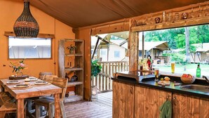 Een houten interieur met een eethoek, een keuken met een bar en uitzicht op de omgeving.