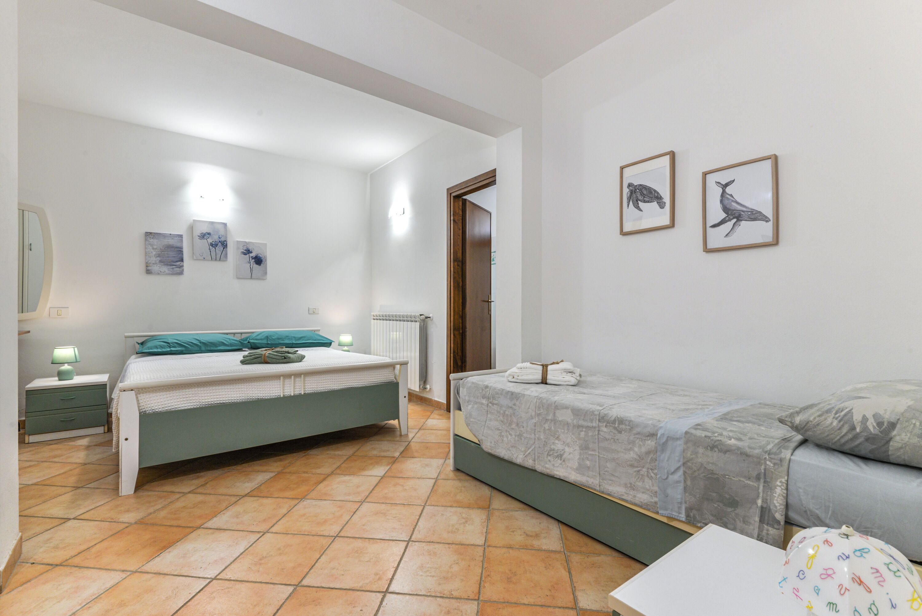 Un dormitorio con dos camas, una mesita de noche, una lámpara y obras de arte en las paredes.