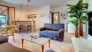 A living room with a sofa, a coffee table, and a dining area with chairs and a table.