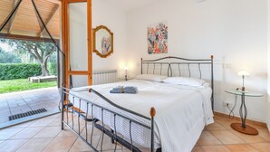 A bedroom with a bed, bedside lamps, a mirror, and artwork on the wall.