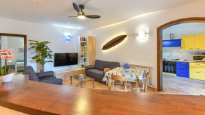A modern living room with a sofa, coffee table, TV, and dining area with chairs and a table.