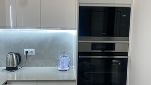 A modern kitchen with white cabinetry, a built-in microwave, and an oven. - Apartamento en Empuriabrava (Empuriabrava)