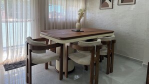 A dining area with a wooden table and chairs, a vase with flowers, and two abstract paintings on the wall. - Apartamento en Empuriabrava (Empuriabrava)