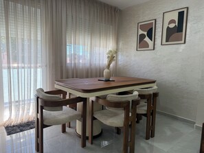 A dining area with a wooden table and chairs, a vase with flowers, and two abstract paintings on the wall. - Apartamento en Empuriabrava (Empuriabrava)