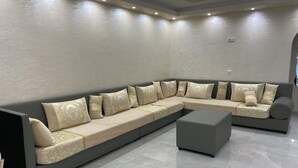A modern living room with a large L-shaped sectional sofa, a grey ottoman, and a tiled floor. - Apartamento en Empuriabrava (Empuriabrava)