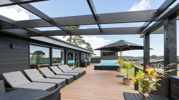 Um deck coberto ao ar livre com cadeiras de lounge e área de piscina.