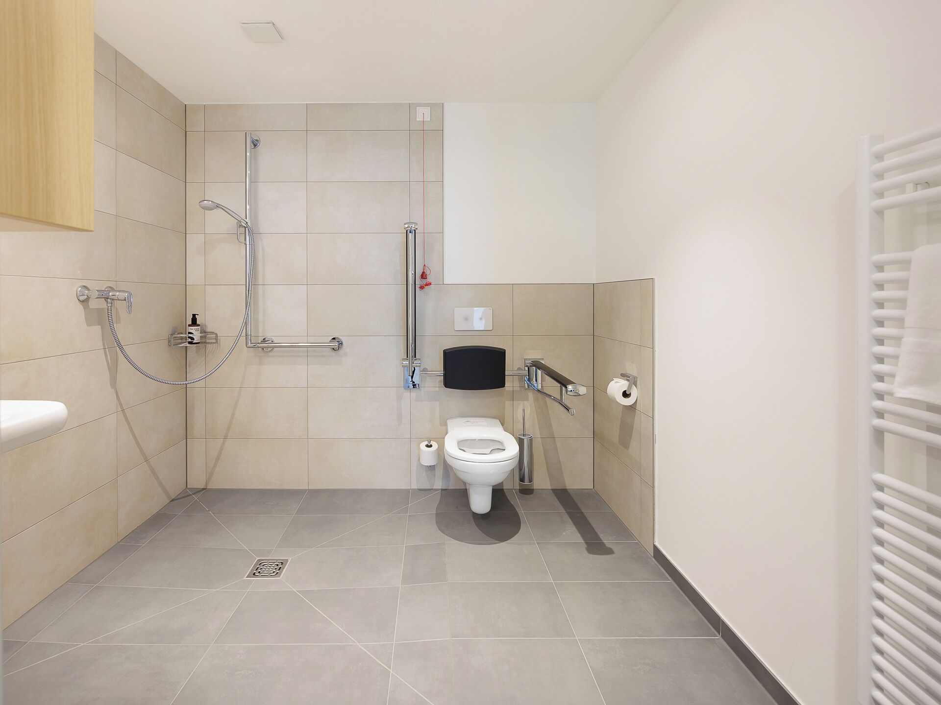 A modern bathroom with a shower, toilet, and hand dryer.