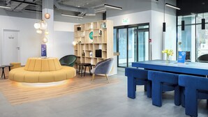 A modern interior with a reception desk, seating area, and a bookshelf. - smartments Frankfurt Airport (Frankfurt)