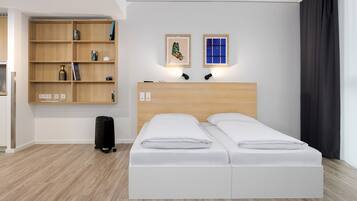A modern hotel room with a double bed, a wooden bookshelf, and a small desk.